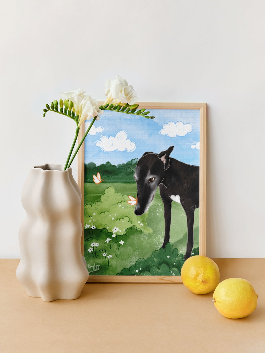 A4 greyhound print sitting framed on a table beside some lemons and a vase