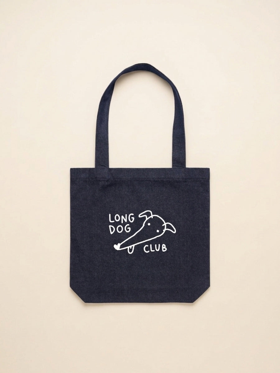Denim tote bag with 'Long Dog Club' text and greyhound drawing on a beige background