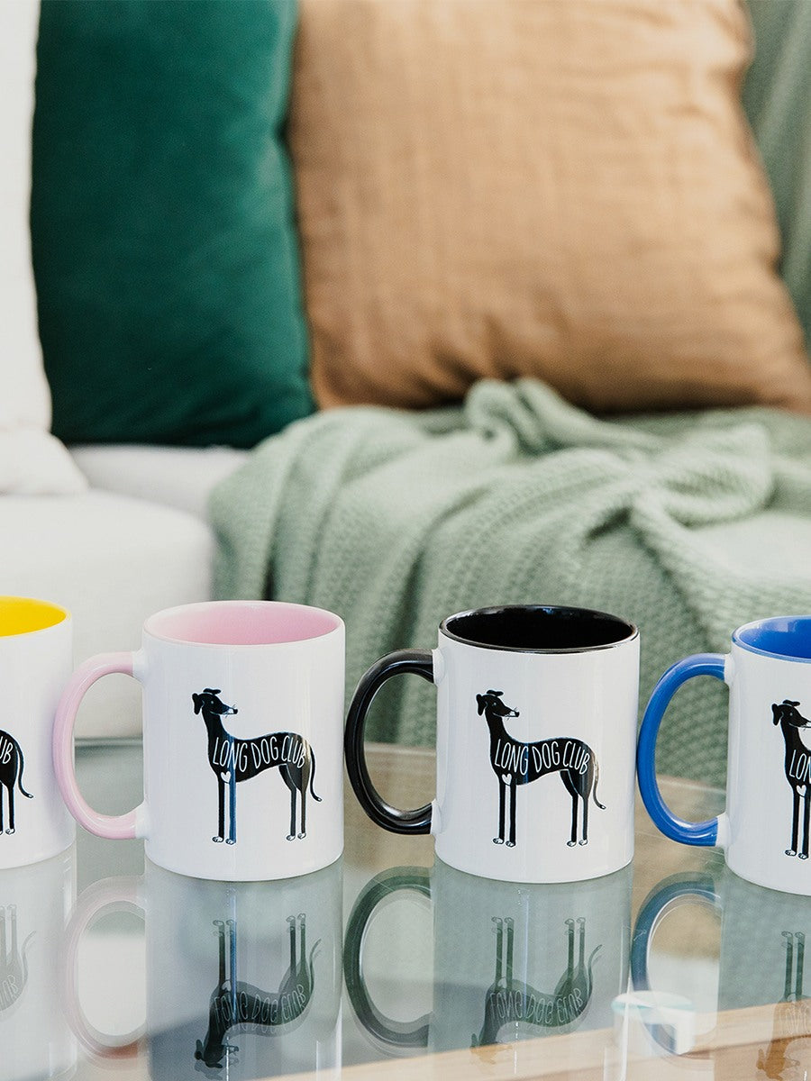 Four greyhound mugs from Long Dog Club sit on a living room coffee table, in different colours