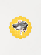 Greyhound sticker with a yellow scalloped border on a light gray background