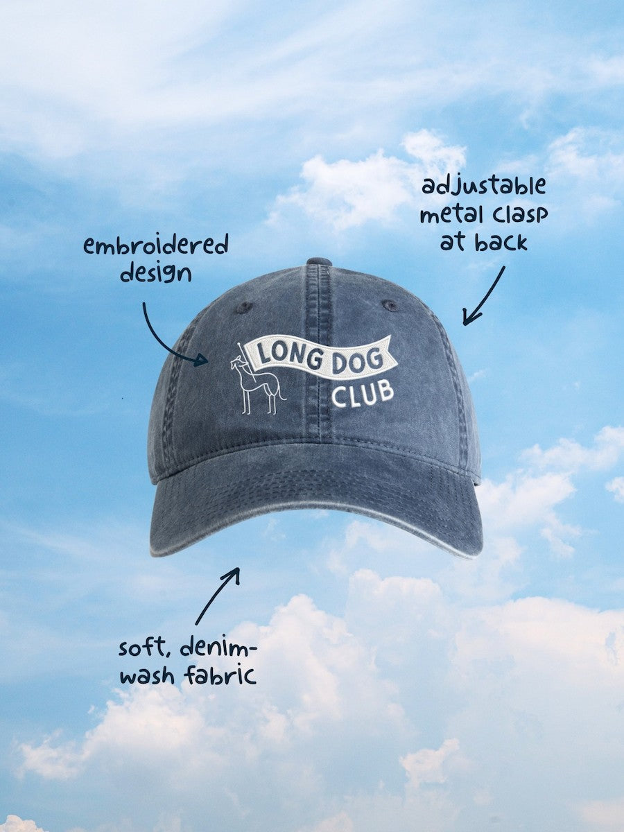 Blue denim cap with 'Long Dog Club' logo against a blue sky background
